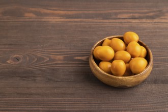 Pile of Smoked Quail eggs in bowl on a brown wooden background. side view, copy space
