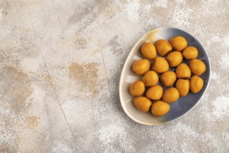 Pile of Smoked Quail eggs on plate on a brown concrete background. top view, flat lay, copy space