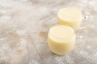 Organic non dairy banana and soy milk in glass on brown concrete background. Vegan healthy food