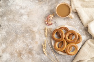 Homemade Ring Bagel with cup of coffee on brown concrete background and linen textile. top view,