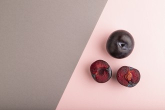 Purple Plum Cut in half on pink and gray pastel paper background. Top view, flat lay, copy space.