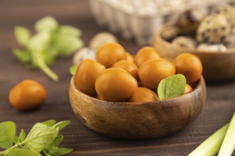 Pile of Smoked Quail eggs in bowl on a brown wooden background. side view, close up, selective