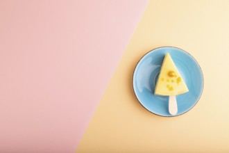 Yellow Cake pop with sprinkles on blue ceramic plate on pink and orange pastel paper background,