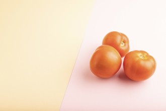 Red tomato on pink and orange pastel paper background. Side view, copy space. healthy food,