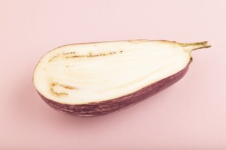 Purple Cutted eggplant with white stripes on pink pastel background. Side view, copy space.
