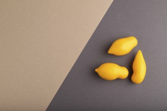 Yellow tomatoes on beige and gray pastel paper background. Top view, copy space, flat lay. healthy