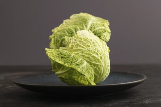 Green lettuce on blue plate on black concrete background. Side view, copy space. healthy food,