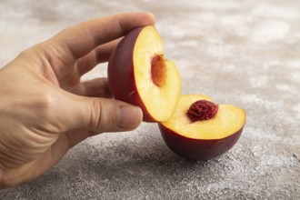 Peach Cut in half with hand on brown concrete background. Side view, copy space. healthy food,