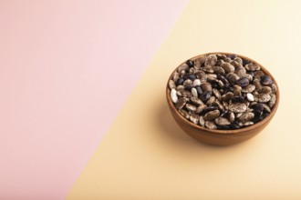 Wooden bowl with Kidney beans on pink and orange pastel paper background, side view, copy space,