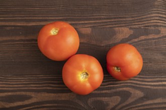 Red tomato on brown wooden background. Top view, flat lay, close up. healthy food, vegetable,