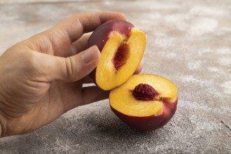 Peach Cut in half with hand on brown concrete background. Side view, copy space. healthy food,