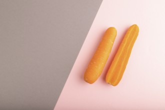 Orange Carrot on gray and pink pastel paper background. Top view, copy space, flat lay. healthy