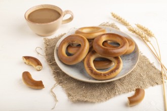 Homemade Ring Bagel with cup of coffee on white wooden background and linen textile. side view,