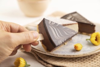 Chocolate and Vanilla Cake pops Marshmallow with hand with cup of coffee on white wooden background
