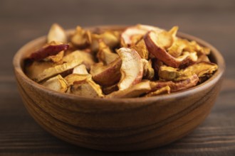 Dried Apples in wooden bowl on brown wooden background. Side view, close up, healthy food,