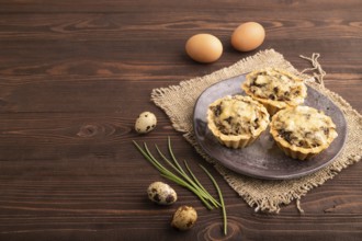 Tartlets with meat and cheese on brown wooden background and linen textile. side view, copy space