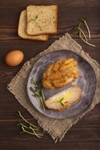Chicken Schnitzel on gray plate with microgreen on brown wooden background and linen textile. top