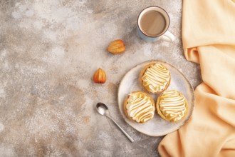 French lemon tart with meringue on brown concrete background, cup of coffee, orange linen textile,