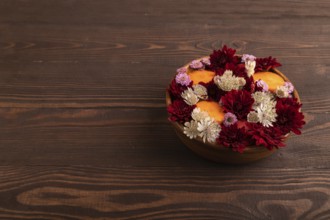 Wooden bowl with carrot slices and red Chrysanthemum flowers, Astrantia flowers, flower salad on