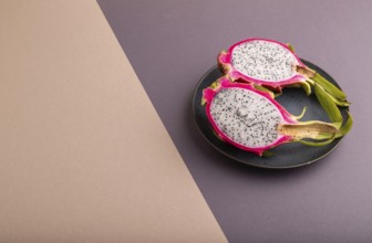 Ripe Pitaya on blue plate on brown and beige pastel paper background, side view, copy space,