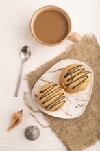 Caramel Cream Cakes on white wooden background and linen textile, cup of coffee, top view, flat