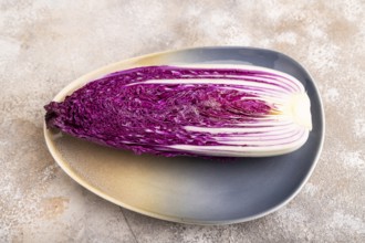 Purple Chinese cabbage on blue plate on brown concrete background, side view, close up, minimalism