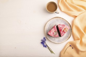 Chocolate cake on white wooden background and orange linen textile, cup of coffee, top view, flat
