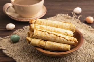 Waffles with caramel on brown wooden background and linen textile, cup of coffee, side view