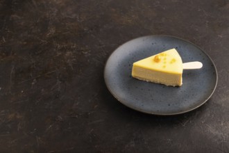 Yellow Cake pop with sprinkles on blue ceramic plate on black concrete background, side view, copy
