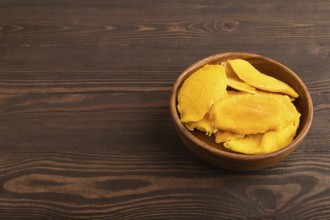 Dried Mango in wooden bowl on brown wooden background. Side view, copy space. healthy food,