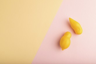 Yellow tomatoes on pink and orange pastel paper background. Top view, copy space, flat lay. healthy