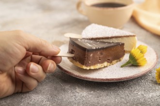 Chocolate and Vanilla Cake pops Marshmallow with hand with cup of coffee on brown concrete
