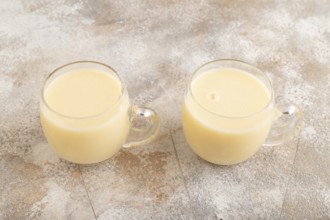 Organic non dairy banana and soy milk in glass on brown concrete background. Vegan healthy food