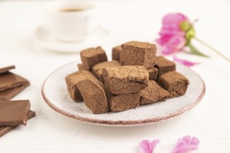 Chocolate marshmallow with cup of coffee on white wooden background. side view, close up, selective