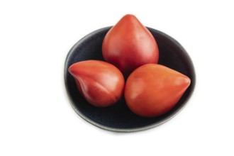 Red Heart shape tomatoes in blue bowl isolated on white background. Side view, copy space, flat lay