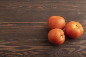 Red tomato on brown wooden background. Side view, copy space. healthy food, vegetable, minimalism
