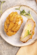 Chicken Schnitzel on blue plate with microgreen on brown concrete background and orange linen