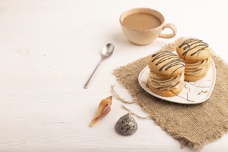Caramel Cream Cakes on white wooden background and linen textile, cup of coffee, side view, copy