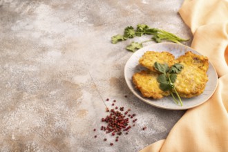 Fried crispy Chicken pancakes on brown concrete background and orange linen textile. side view,