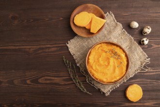 Sweet potato porridge in wooden bowl on wooden background and linen textile. Diet, healthy eating
