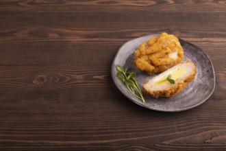 Chicken Schnitzel on gray plate with microgreen on brown wooden background. side view, copy space