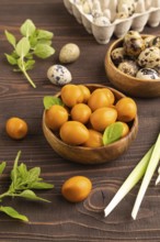 Pile of Smoked Quail eggs in bowl on a brown wooden background. side view, close up