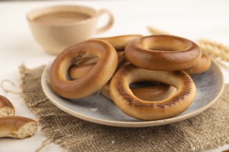 Homemade Ring Bagel with cup of coffee on white wooden background and linen textile. side view,