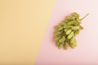 Green grapes on orange and pink paper pastel background. Top view, flat lay, copy space. healthy