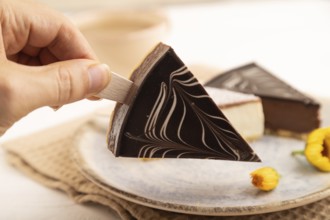 Chocolate and Vanilla Cake pops Marshmallow with hand with cup of coffee on white wooden background