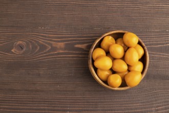 Pile of Smoked Quail eggs in bowl on a brown wooden background. top view, flat lay, copy space