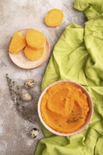 Sweet potato porridge in ceramic bowl on brown concrete background and green textile. Diet, healthy
