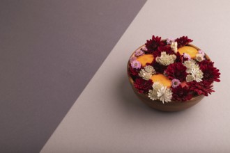 Wooden bowl with carrot slices and red Chrysanthemum flowers, Astrantia flowers, flower salad on