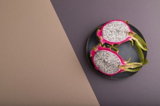 Ripe Pitaya on blue plate on brown and beige pastel paper background, top view, flat lay, copy