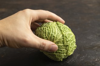 Green lettuce with hand on black concrete background. Side view, copy space. healthy food,